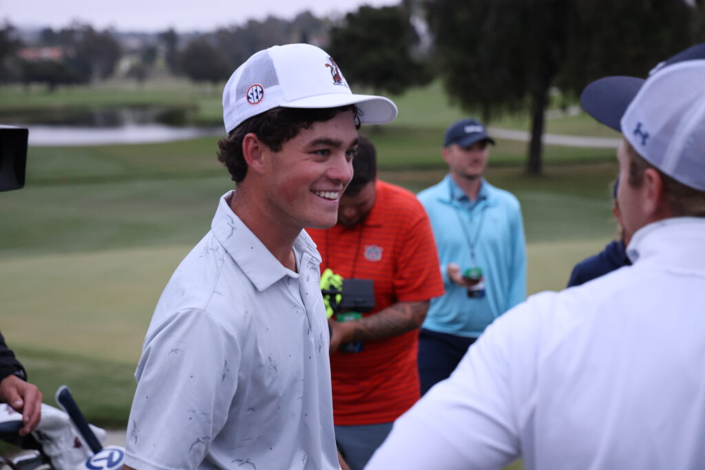 Jackson Koivun smiles with teammates after winning his match to advance Auburn to the championship.