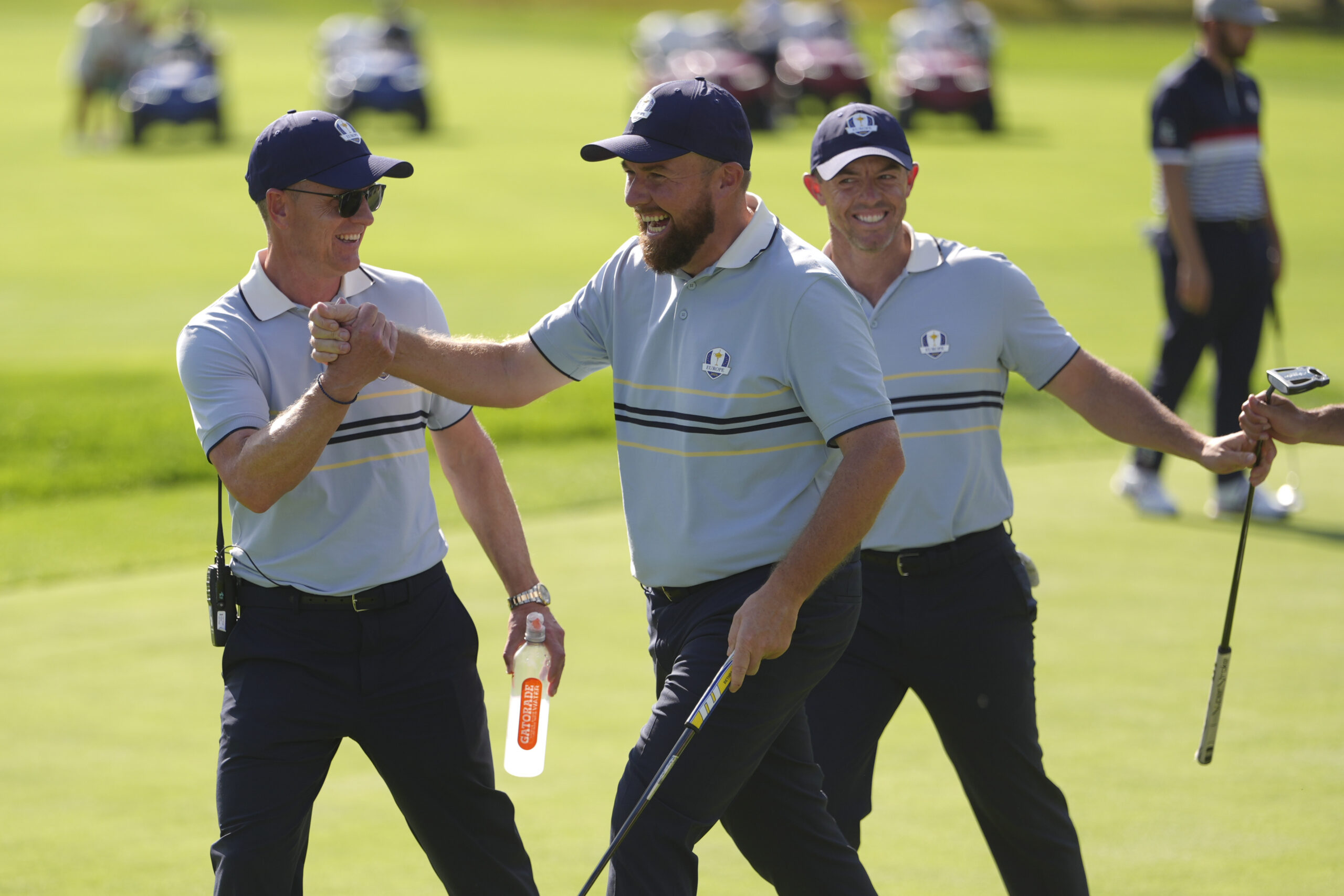 Captain Luke Donald, Shane Lowry, and Rory McIlroy of Team Europe react on the seventh hole green during the 2025 Ryder Cup.