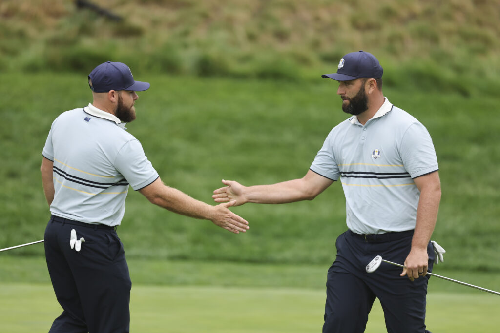 Jon Rahm high fives Tyrrell Hatton of Team Europe after his putt on the eighth hole during the 2025 Ryder Cup.