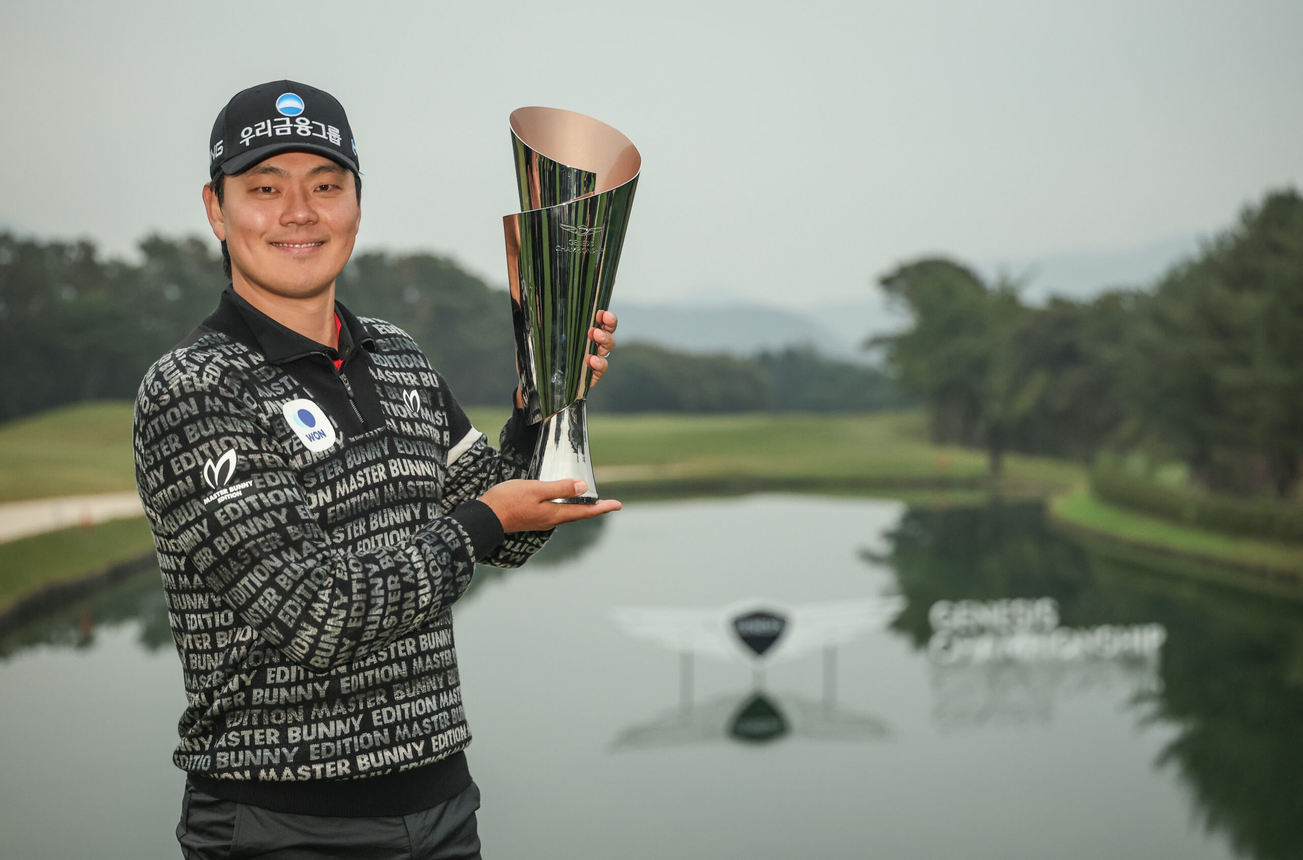 South Korea's Junghwan Lee poses with the Genesis Championship trophy on the 18th green following his victory.