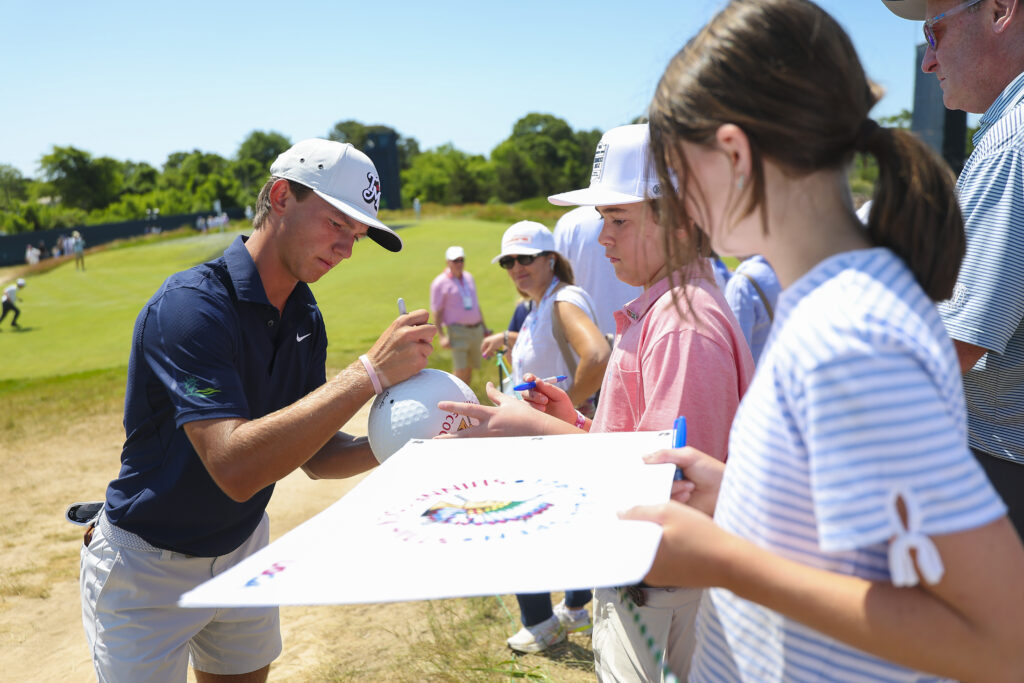 Miles Russell signs autographs for fans during a practice round ahead of the 2026 U.S. Open.