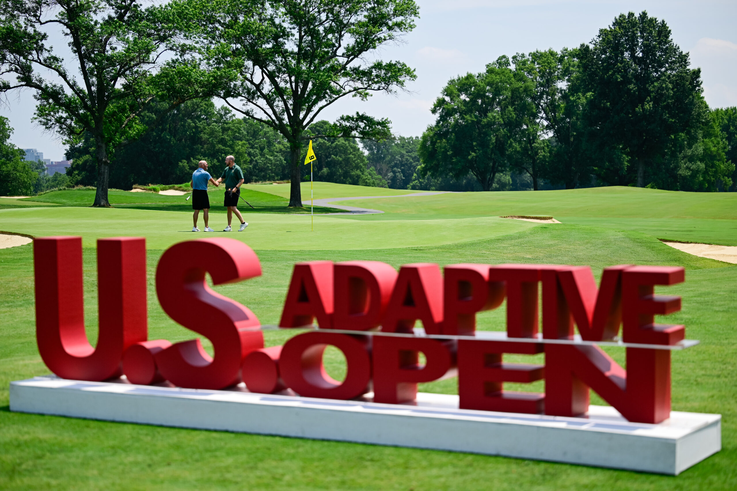 Jonathan Chown and Joshua Philbeck interact on the ninth hole after sinking their putts during a practice round ahead of the 2026 U.S. Adaptive Open at Woodmont Country Club