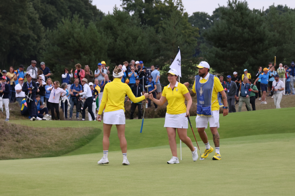 Charley Hull fist bumps Lottie Woad after the latter made birdie on the 17th hole.